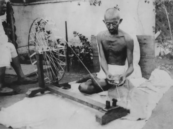 Mahatma Gandhi at the spinning wheel (charkha), a symbol of Indian self-reliance and resistance